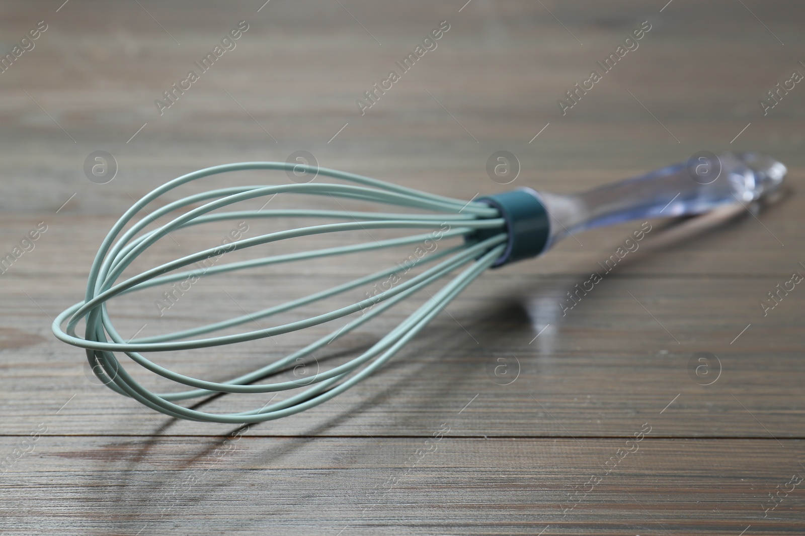 Photo of One whisk on wooden table, closeup. Kitchen tool