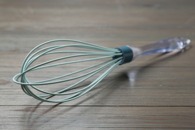 Photo of One whisk on wooden table, closeup. Kitchen tool