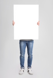 Photo of Man holding blank poster on light grey background