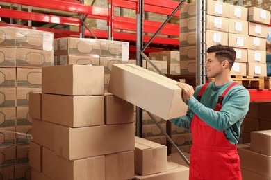 Photo of Worker stacking cardboard boxes in warehouse. Wholesaling
