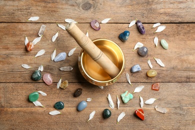 Flat lay composition with golden singing bowl on wooden table. Sound healing
