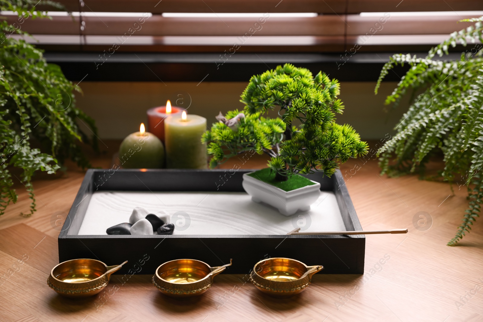 Photo of Beautiful miniature zen garden, candles and oil lamps near window indoors