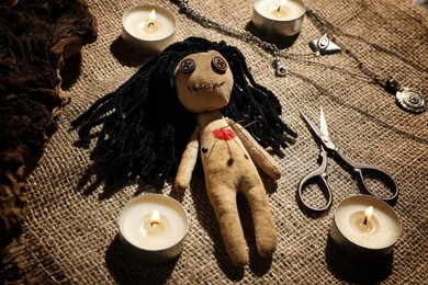 Voodoo doll with pins surrounded by ceremonial items on burlap fabric