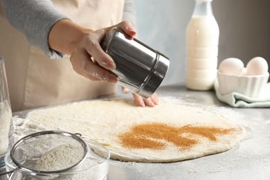 Woman making cinnamon rolls at table, closeup