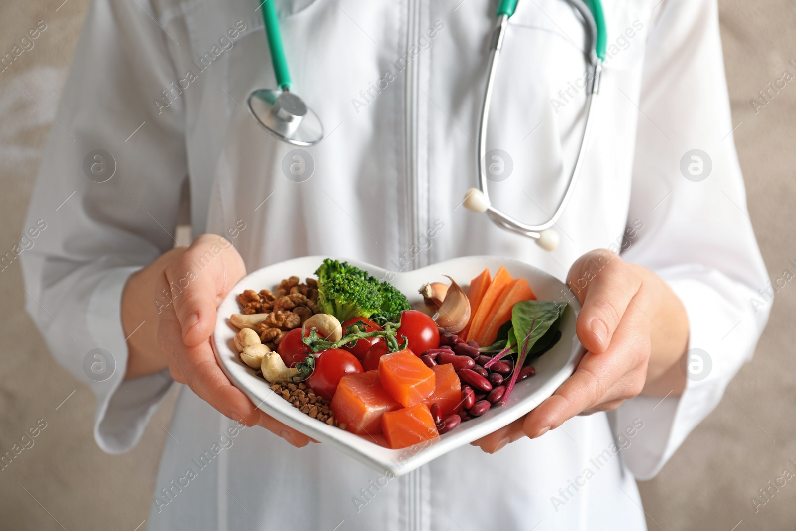 Photo of Doctor holding plate with products for heart-healthy diet, closeup