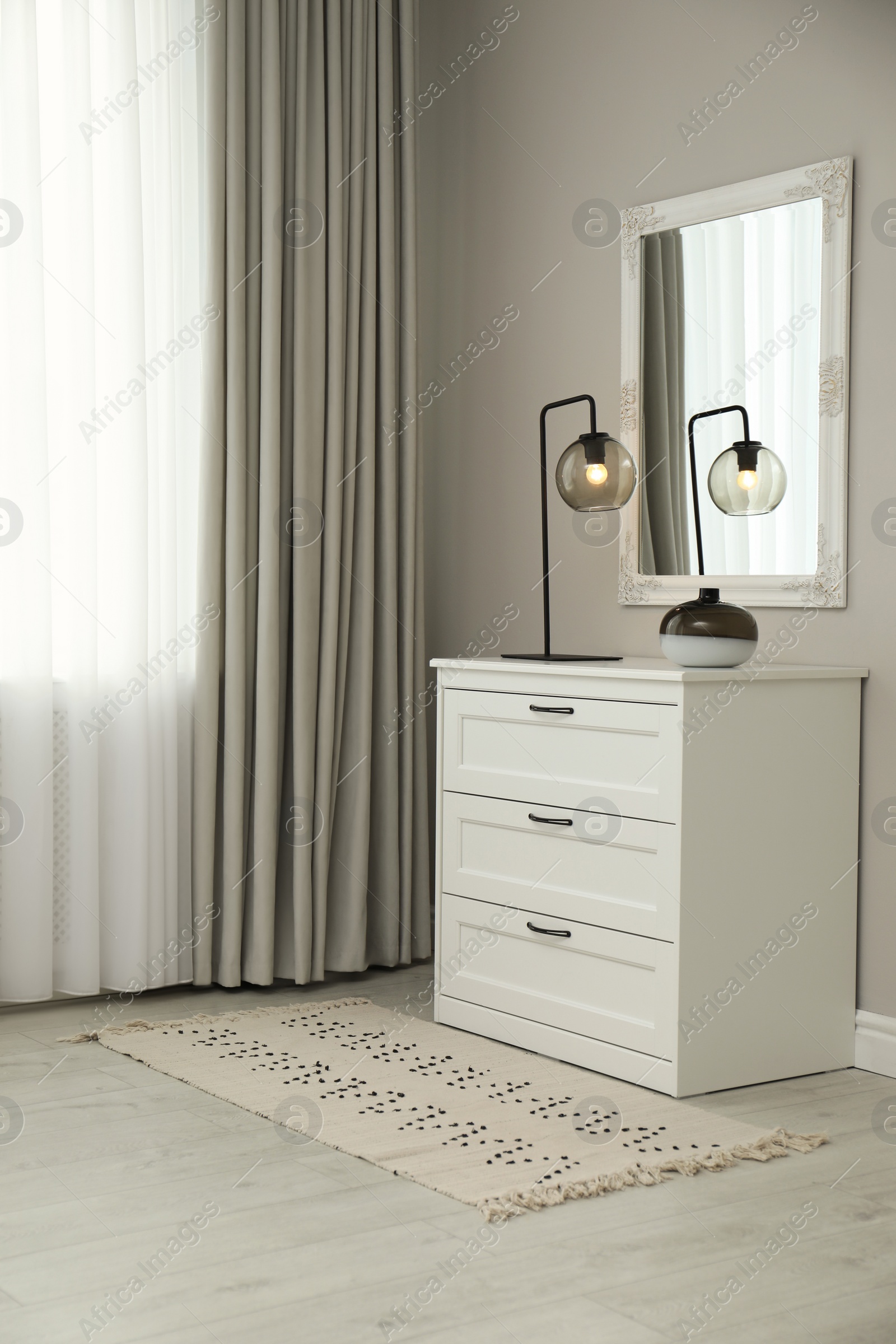 Photo of Hallway with stylish chest of drawers and mirror. Interior design