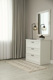 Photo of Hallway with stylish chest of drawers and mirror. Interior design