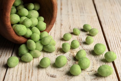 Tasty wasabi coated peanuts on white wooden table, closeup