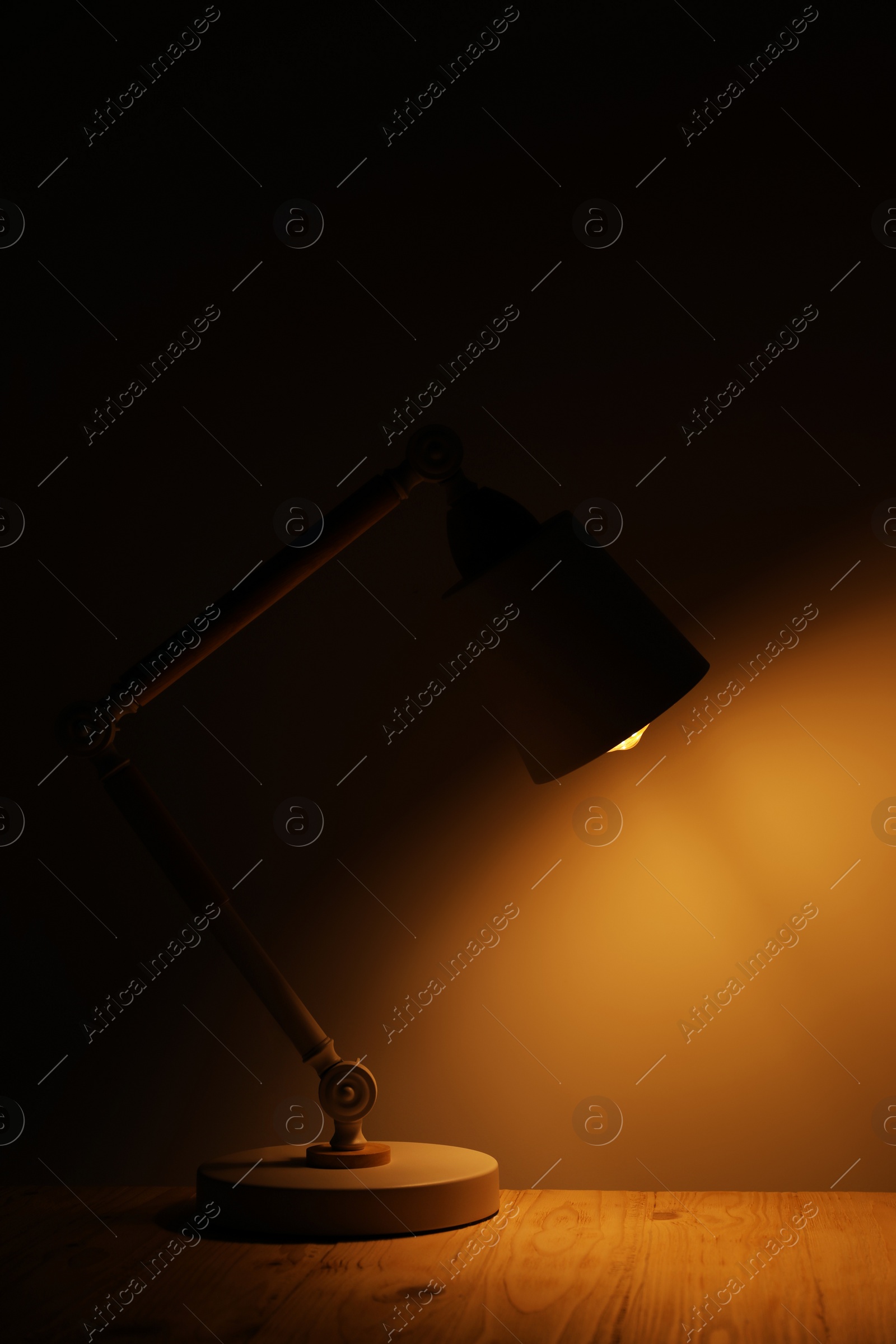 Photo of Stylish modern desk lamp on wooden table at night