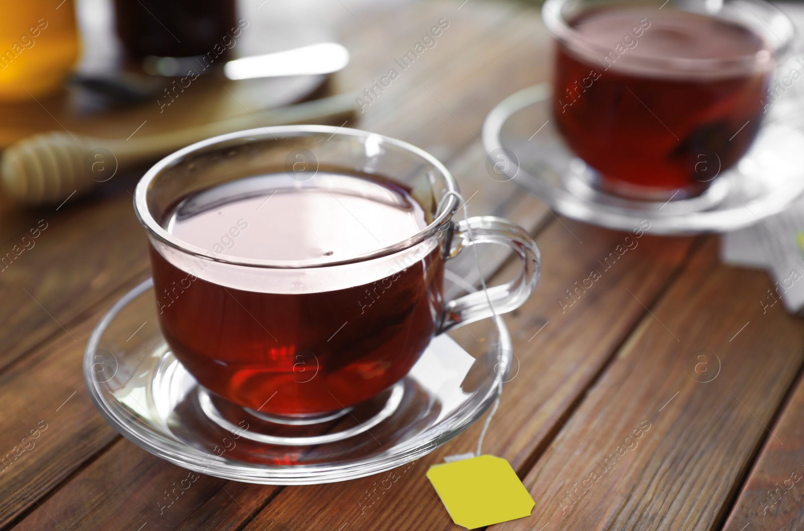 Photo of Tea bag in glass cup on wooden table, closeup. Space for text