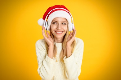 Photo of Happy woman with headphones on yellow background. Christmas music