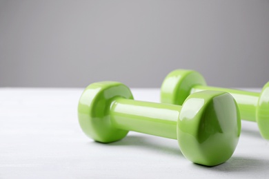 Bright dumbbells on white table, space for text. Home fitness