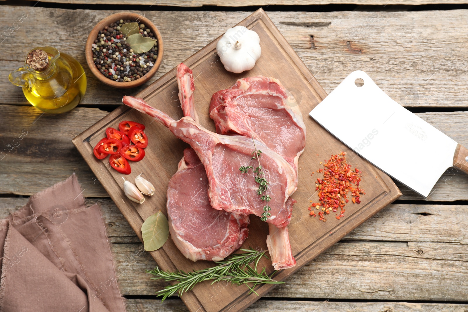 Photo of Fresh tomahawk beef cuts, butcher knife and spices on wooden table, top view