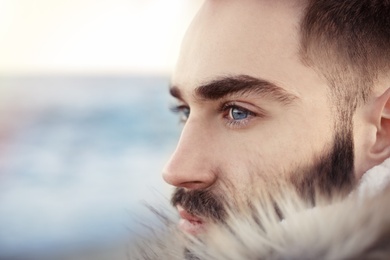 Photo of Portrait od bearded handsome man near sea, closeup view. Space for text
