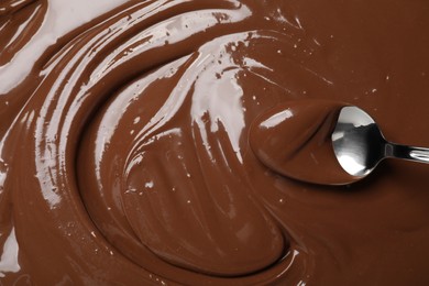 Spoon with tasty milk chocolate paste as background, top view