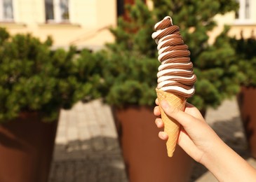 Photo of Woman holding delicious ice cream outdoors, closeup. Space for text