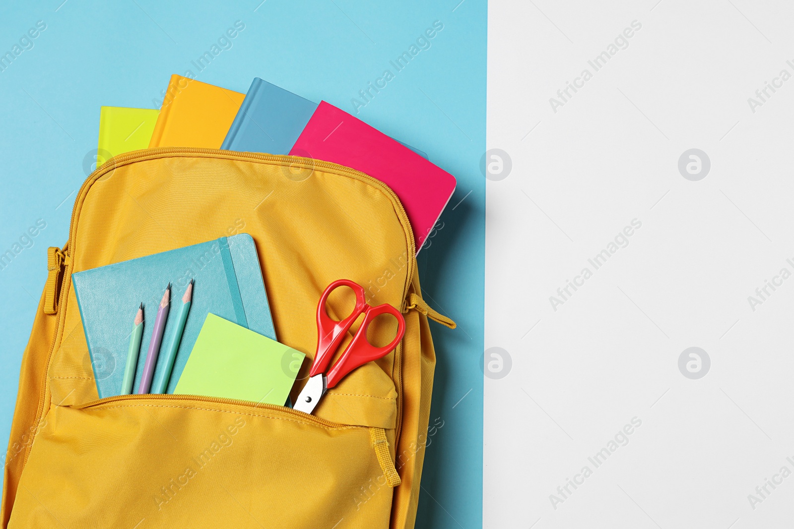 Photo of Backpack with different school stationery on color background, top view. Space for text