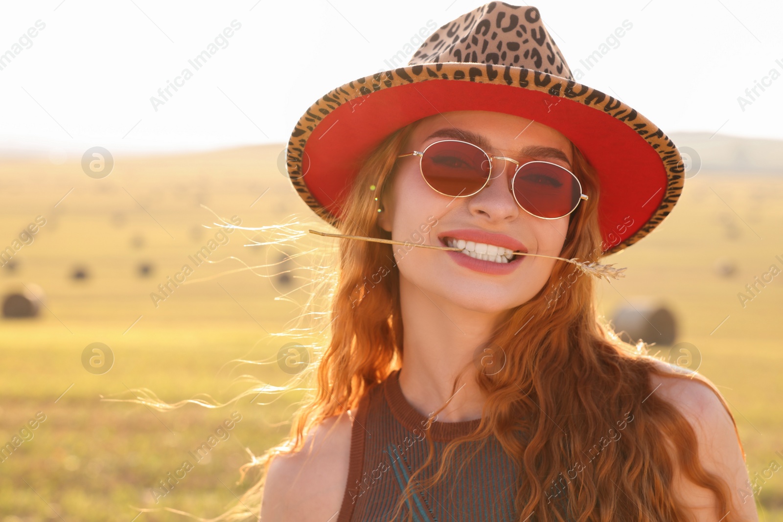 Photo of Beautiful happy hippie woman with spikelet in field, space for text