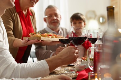 Photo of Family clinking glasses of wine at festive dinner, focus on hands. Christmas celebration