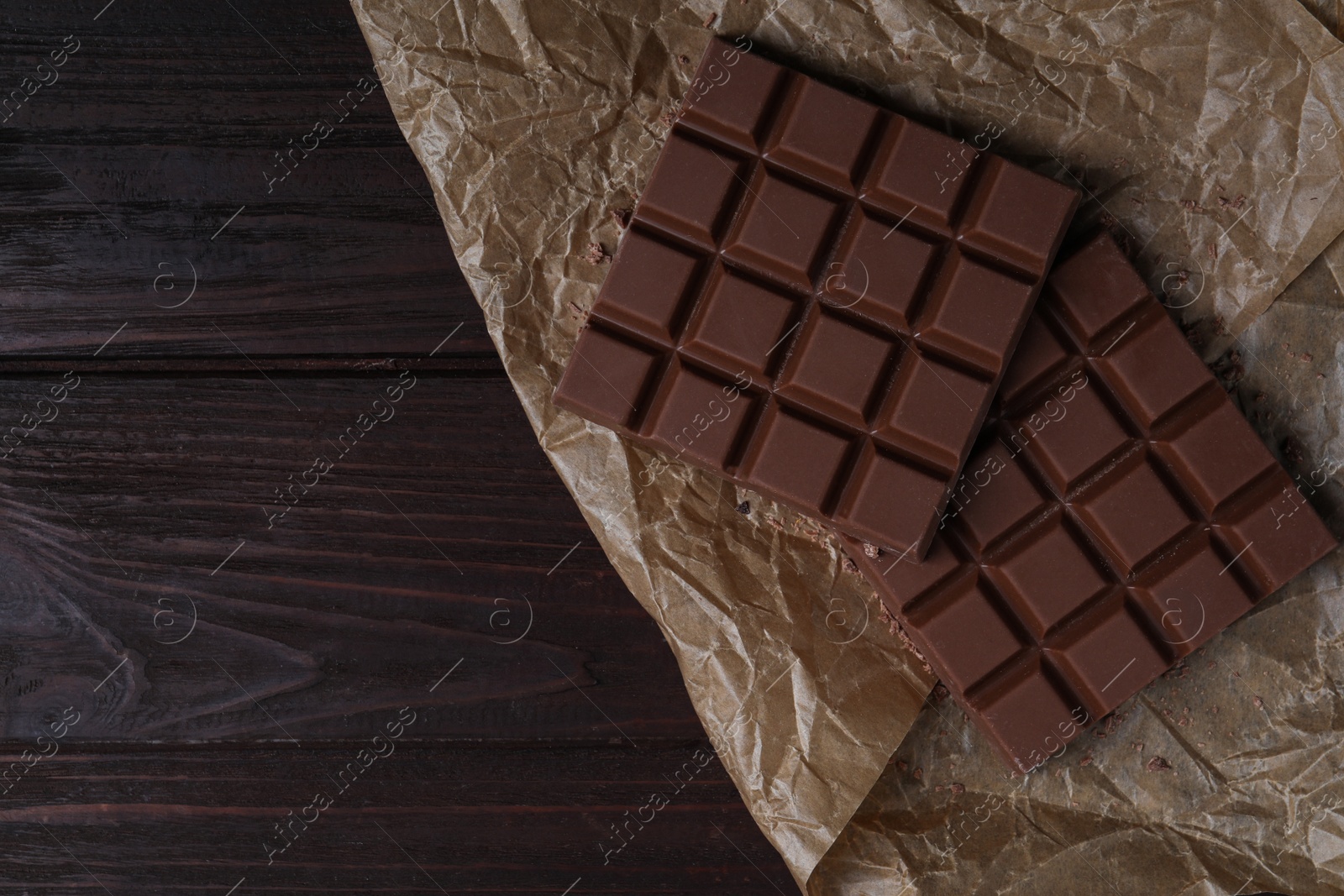 Photo of Tasty milk chocolate bars on wooden table, flat lay. Space for text