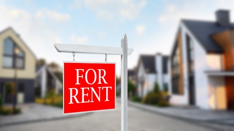Image of Sign with phrase FOR RENT and blurred view of beautiful houses