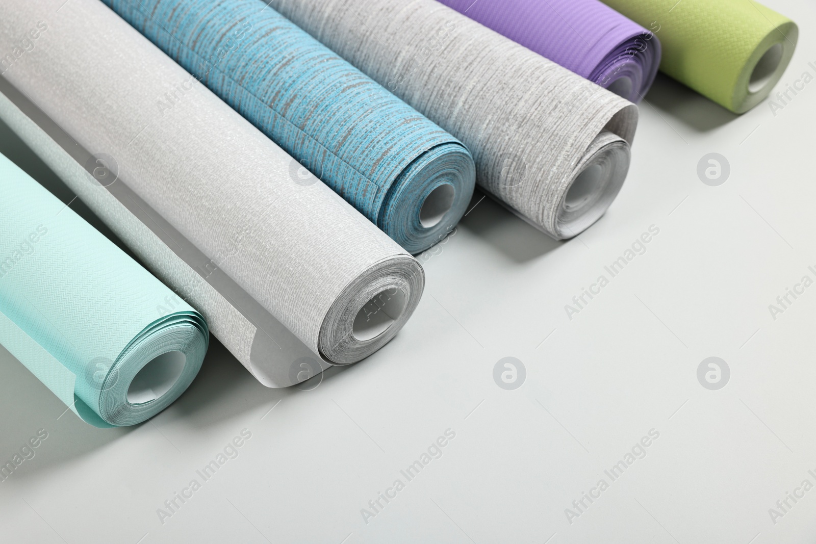 Photo of Different wallpaper rolls on light background. Space for text