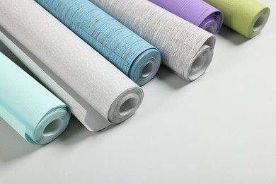 Photo of Different wallpaper rolls on light background. Space for text