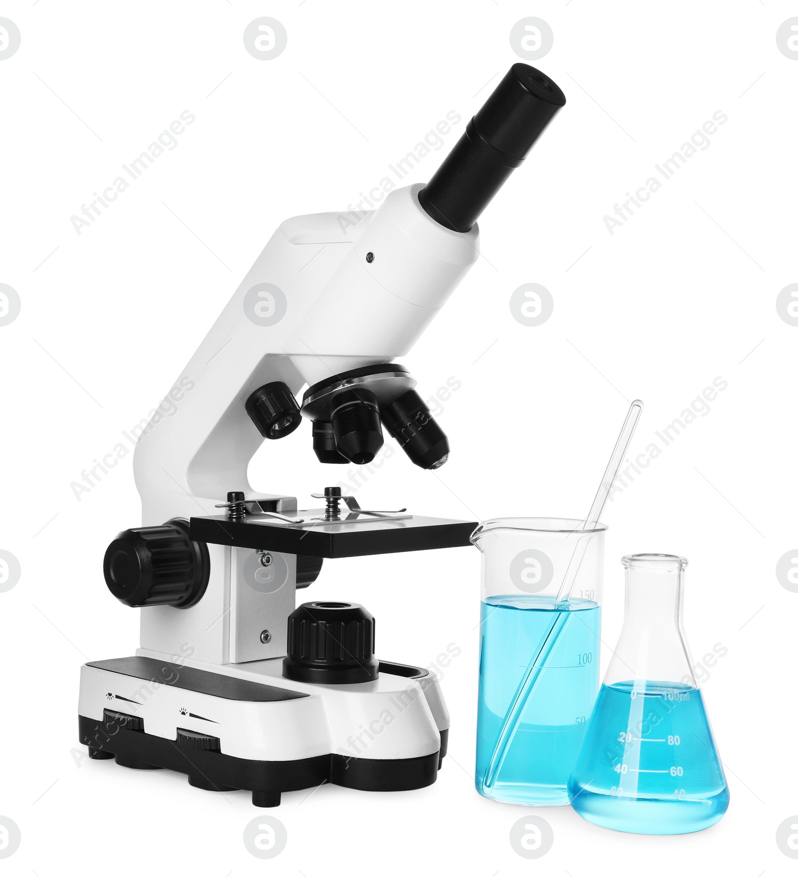 Photo of Laboratory glassware with light blue liquid and microscope isolated on white