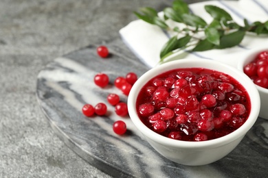 Fresh cranberry sauce in white bowl on marble board, space for text