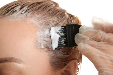 Photo of Young woman dyeing her hair against white background, closeup