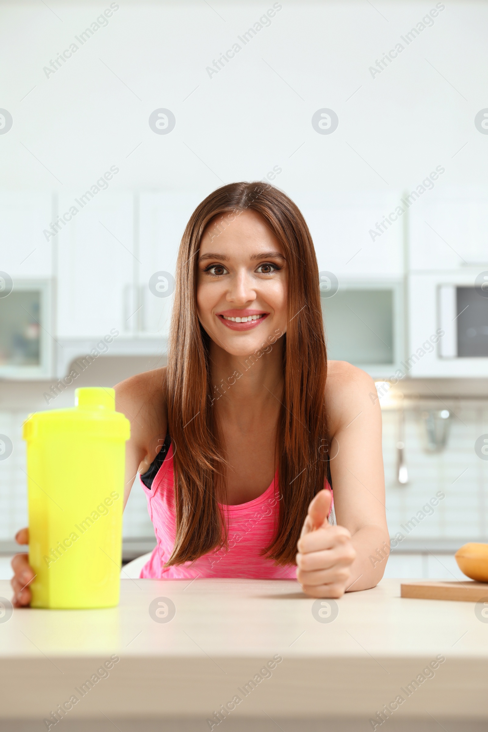 Photo of Young woman with bottle of protein shake in kitchen