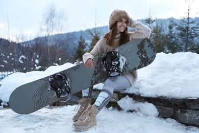 Photo of Young snowboarder wearing winter sport clothes outdoors
