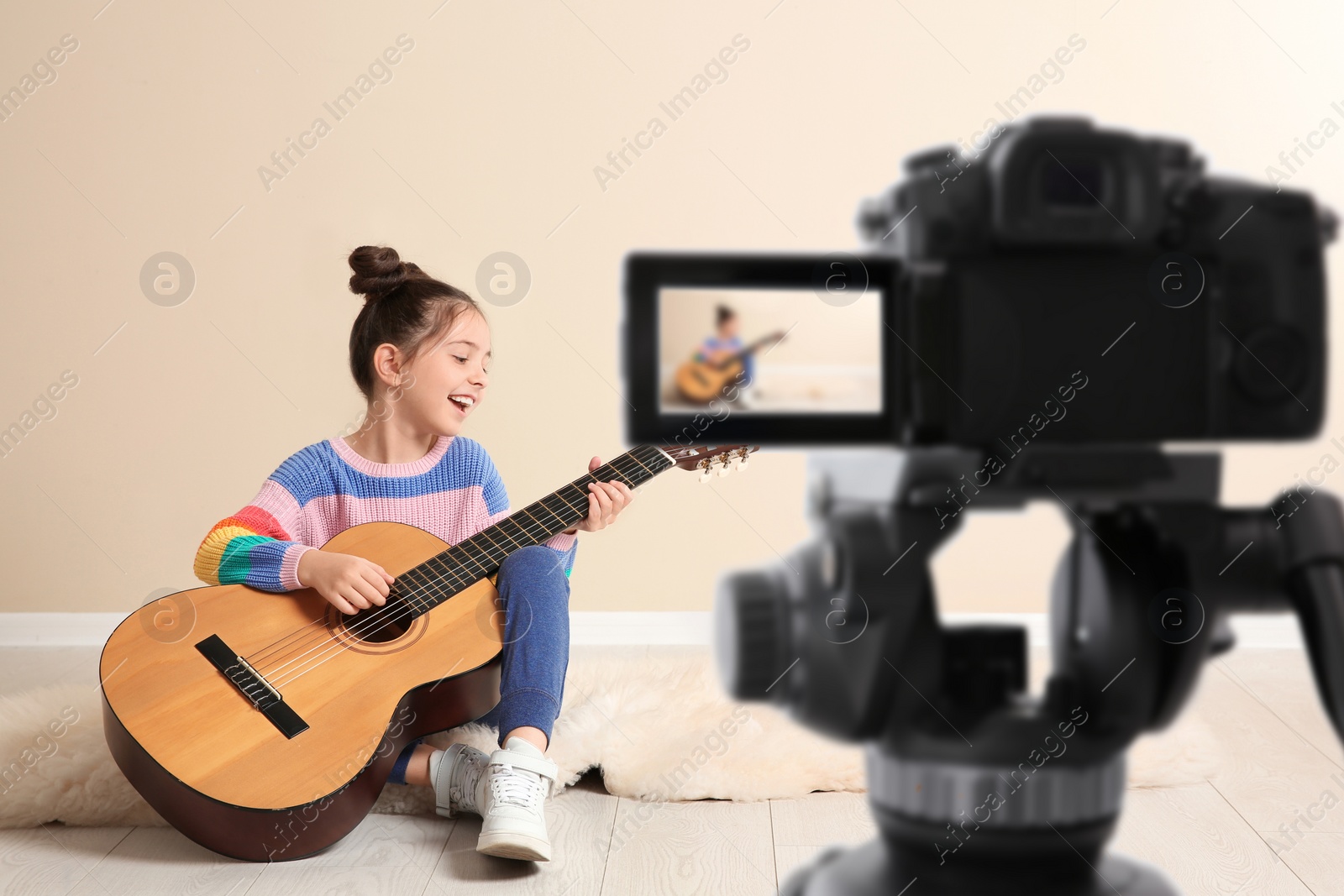 Image of Little music teacher recording guitar lesson indoors