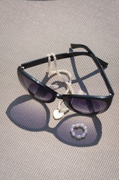 Photo of Stylish sunglasses and jewelry on grey surface