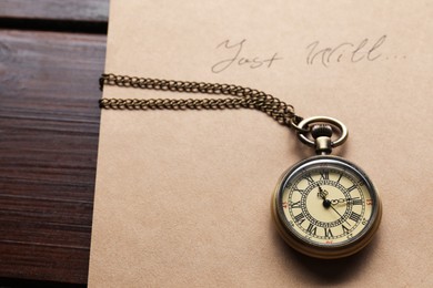 Paper with words Last Will and pocket watch on wooden table, closeup