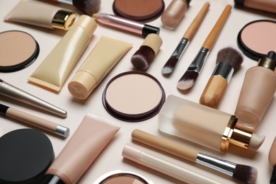 Face powders and other makeup products on beige background, closeup