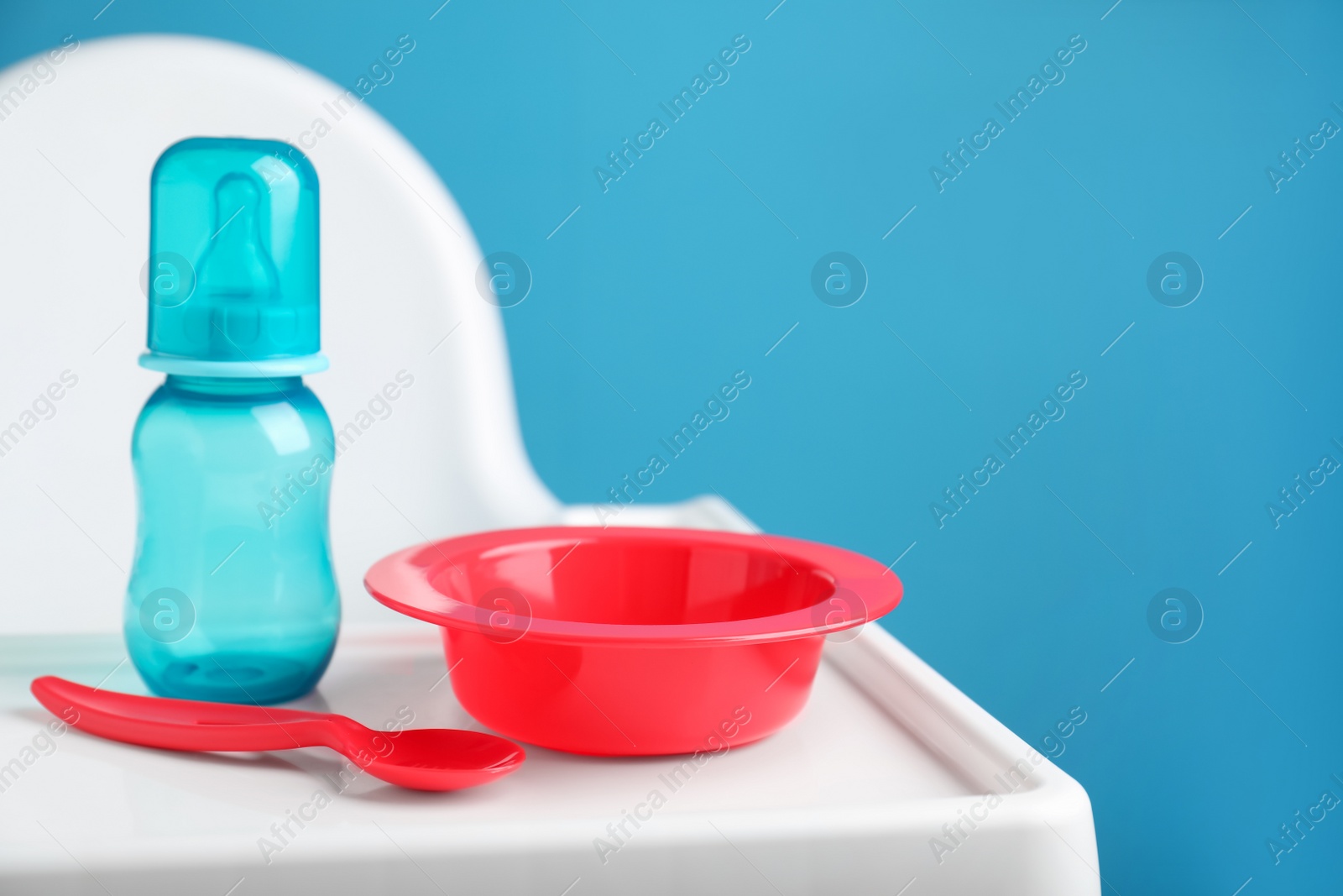 Photo of Set of plastic dishware on white feeding table. Serving baby food