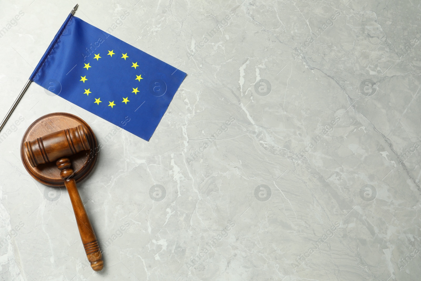 Photo of Judge's gavel and flag of European Union on light grey marble table, flat lay. Space for text