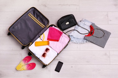 Photo of Packed suitcase on wooden background, top view. Space for text