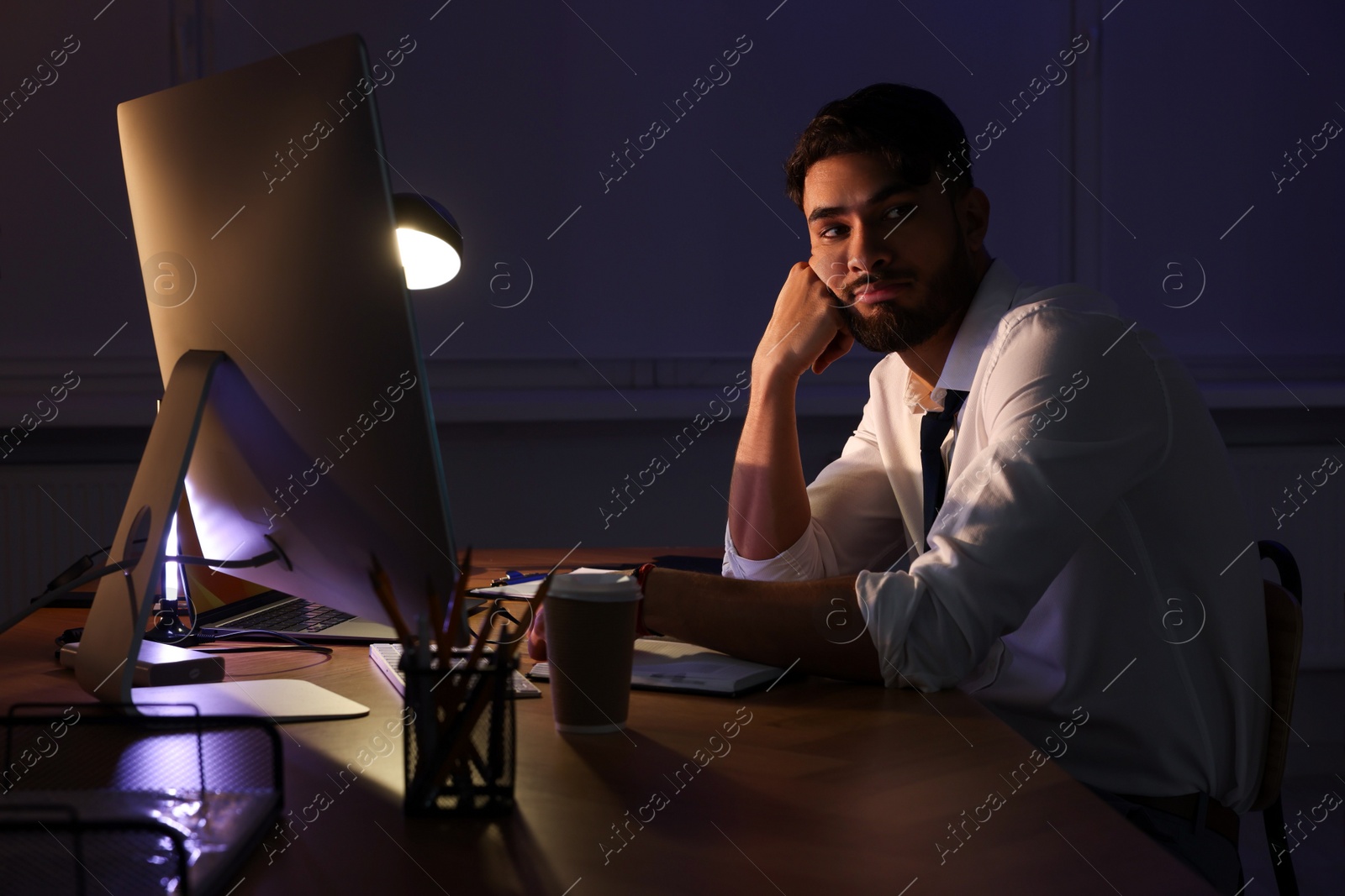 Photo of Tired young man working late in office