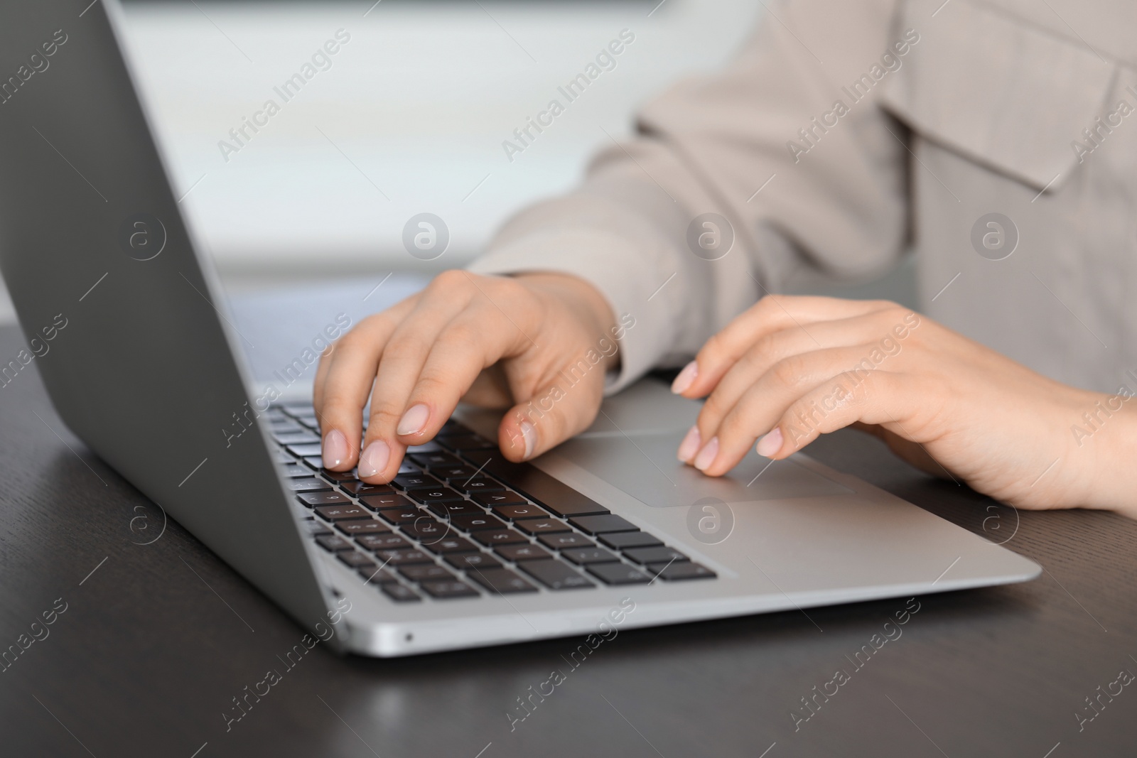 Photo of Woman working on laptop at table, closeup. Electronic document management