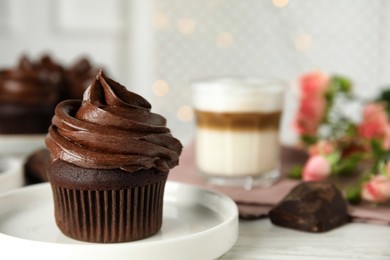 Photo of Plate with delicious chocolate cupcake on white table. Space for text