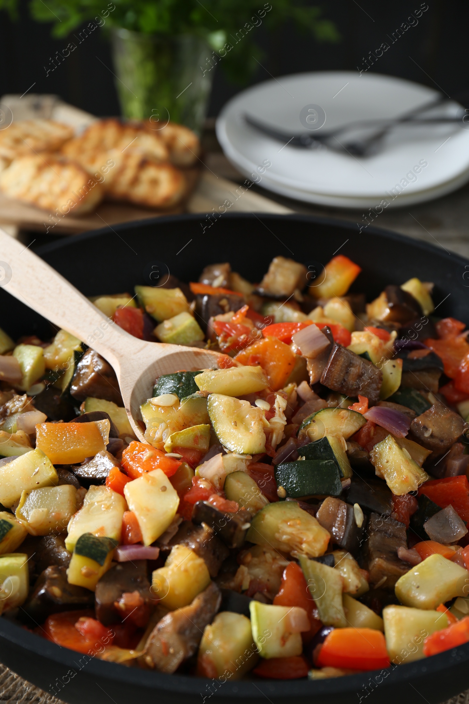 Photo of Delicious ratatouille and spoon in baking dish on table, closeup