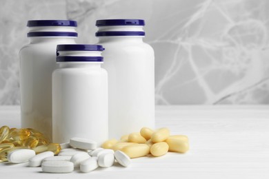 Photo of Medical bottles and pills on white wooden table, space for text
