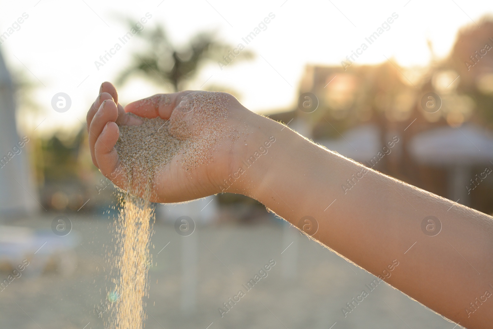 Photo of Girl pouring sand from hand on beach, closeup. Fleeting time concept