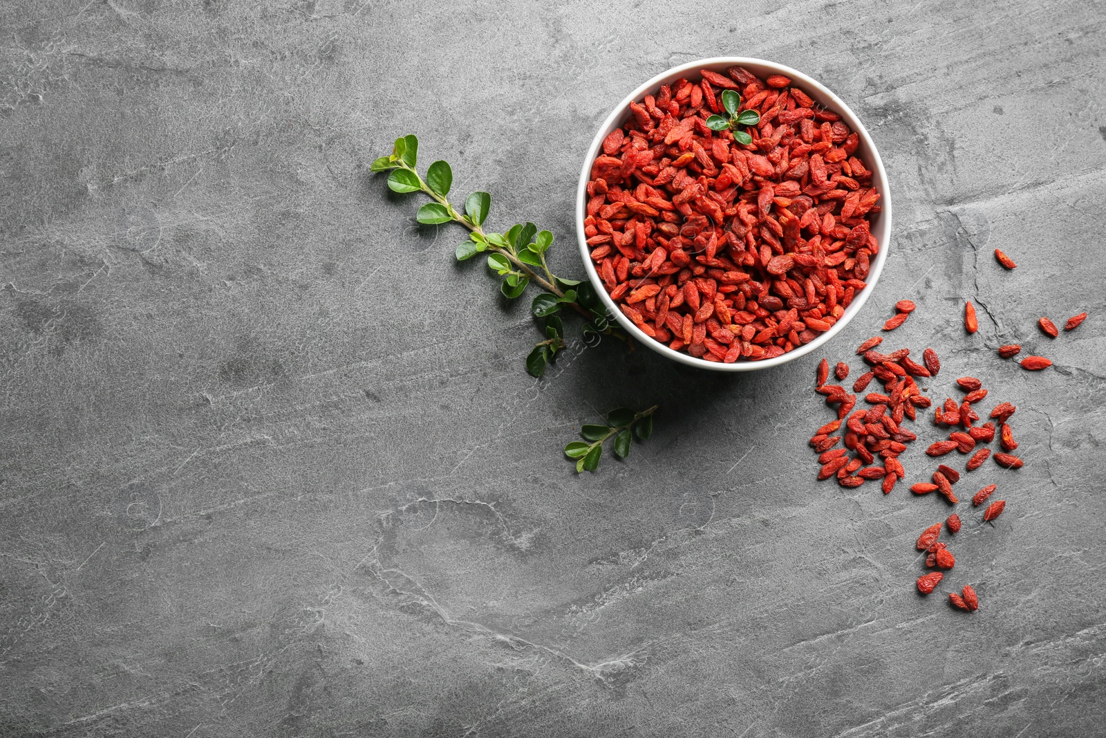 Photo of Flat lay composition with dried goji berries on grey table, space for text. Healthy superfood