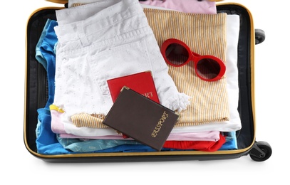 Packed suitcase with clothes and passports on white background, above view