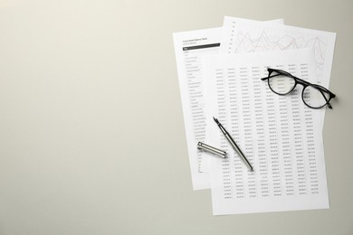 Photo of Accounting documents, fountain pen and glasses on beige table, top view. Space for text