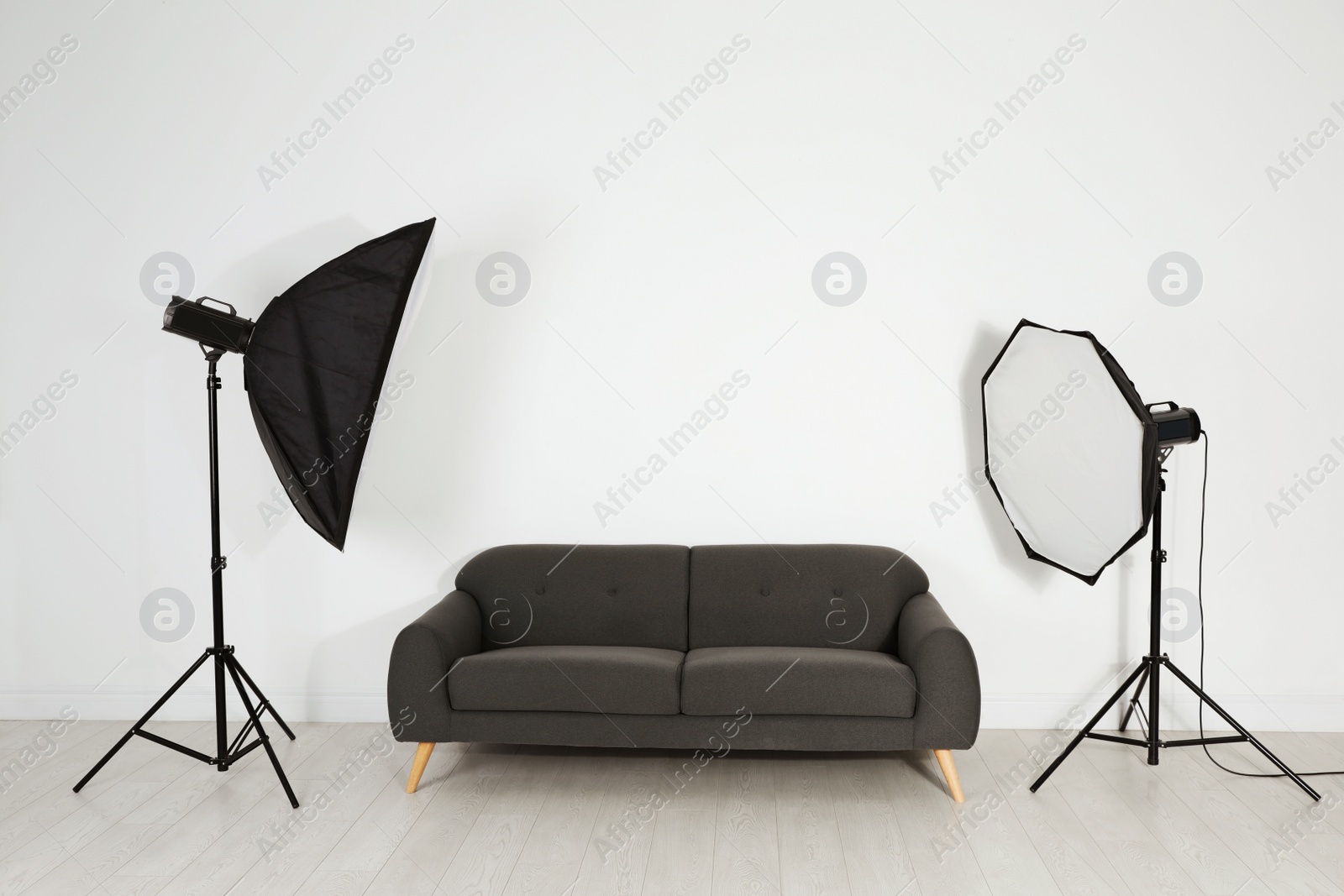 Photo of Comfortable sofa and professional lighting equipment in photo studio