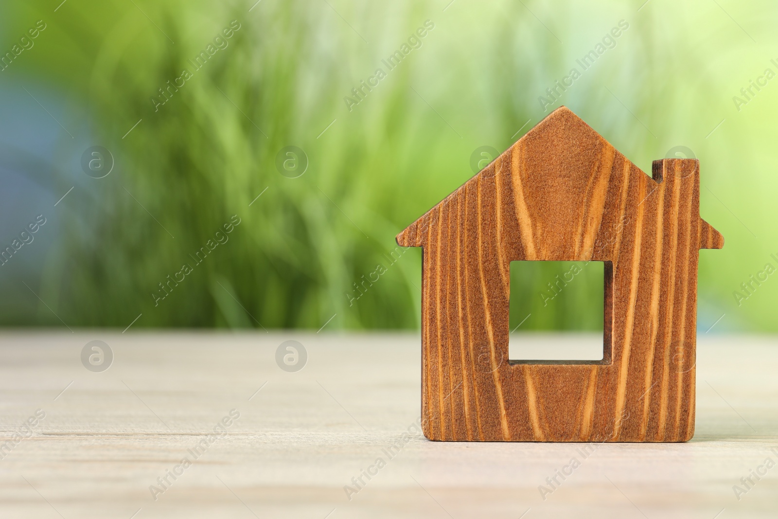 Photo of Mortgage concept. House model on white wooden table against blurred green background, space for text